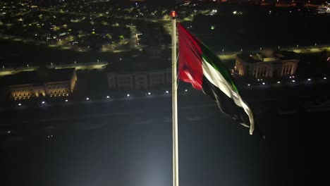 4K:-Aerial-night-view-of-UAE-Flag-waving-in-the-air,-The-national-symbol-of-the-United-Arab-Emirates