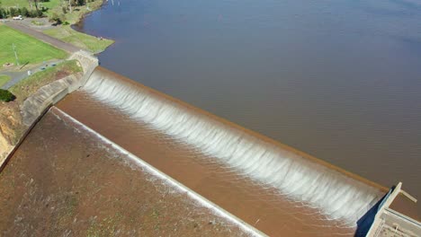 Rising-aerial-footage-of-water-spilling-over-the-Upper-Coliban-Reservoir-spillway,-central-Victoria,-Australia