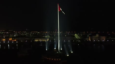 4K:-Aerial-night-view-of-the-UAE-Flag-waving-in-the-air,-The-national-symbol-of-the-United-Arab-Emirates