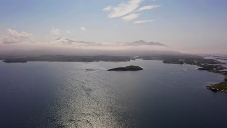 Aerial-view-of-clouds-rolling-over-the-mainland-at-the-coast-of-the-Atlantic-sea,-summer-in-Norway---rising,-drone-shot