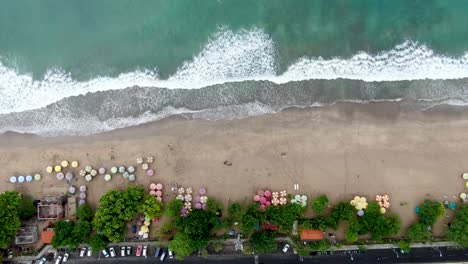 Tropical-exotic-beach-with-umbrellas-and-blue-water-ocean,-aerial-top-down-view