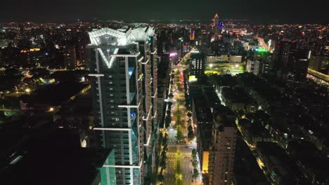 Aerial-backwards-shot-of-taipei-towers-on-zhongxiao-avenue-at-night---Illuminated-city-in-Asia