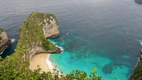Small-blue-ocean-bay-and-sandy-beach-in-Nusa-Penida,-pan-right-view