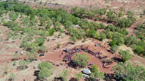 Aerial-view-pulling-up-and-out-of-the-cermony-at-the-start-of-the-Freedom-Day-Festival-and-the-community-of-Kalkaringi-in-the-background,-Northern-Territory,-Australia