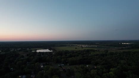 A-drone-shot-of-a-beautiful-vast-land-along-with-a-small-canal-in-the-evening-time-with-clean-blue-sky-background
