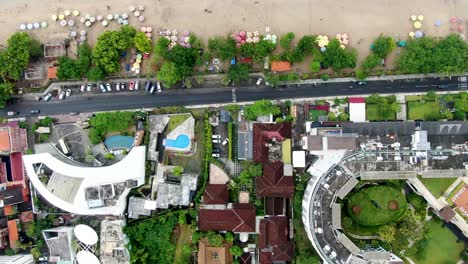 Coastal-road-and-luxury-resort-town-near-Kuta-beach-in-Bali,-aerial-top-down