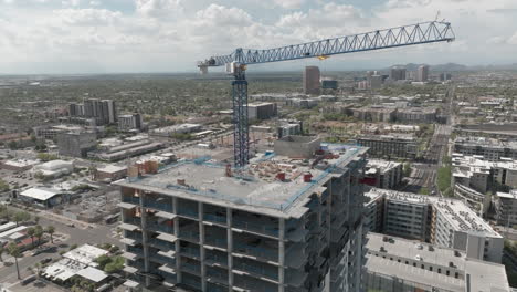 Rotating-drone-shot-of-crane-on-top-of-a-hotel-construction-project