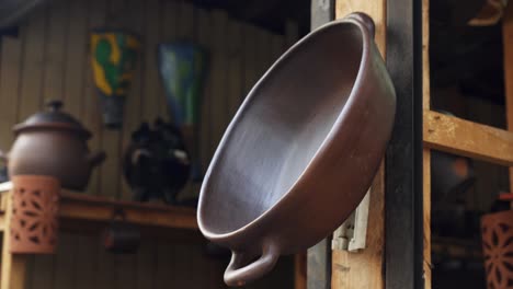 Pomaire-Keramik---Tontopf-Mit-Griff,-Der-An-Einem-Holzpfosten-In-Einem-Geschäft-In-Pomaire,-Chile,-Hängt