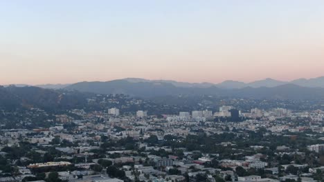 Skyline-Der-Stadt-Bei-Sonnenuntergang-In-Los-Angeles-Mit-Bergen-Im-Hintergrund,-Die-Sich-Nach-Links-über-Die-Stadt-Bewegen