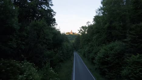 Drone-shot-towards-braunfels-castle-over-an-avenue-between-the-woods-in-germany