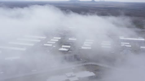 Fog-covering-NjarÃ°vÃ­k-town-in-Iceland-with-several-buildings,-aerial