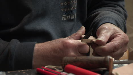 Craftsman's-hands-rasping-a-small-piece-of-wood-with-a-file