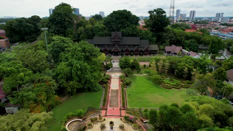 Drone-captures-the-Melaka-Sultanate-Palace-Museum-in-Malacca-City,-Malaysia-surrounded-by-green-trees-on-a-cloudy-day