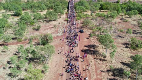 Rising-drone-view-of-crowds-crossing-the-bridge-over-the-Victoria-River-in-the-Freedom-Day-Festival-march-in-the-remote-community-of-Kalkaringi,-Northern-Territory,-Australia