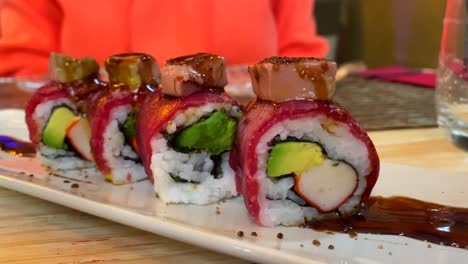 Delicious-inside-out-uramaki-sushi-roll-with-wagyu-steak-and-foie-gras-in-a-japanese-restaurant,-4K-shot