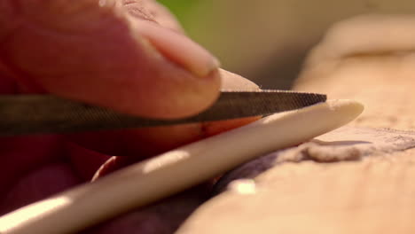 Extreme-close-up-craftsman-filing-ivory-sharp-utensil,-Viking-Experience
