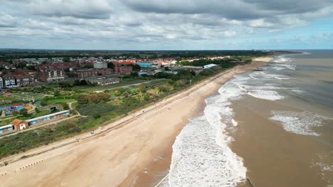 Typical-English-seaside-resort,-shot-using-a-drone,-giving-a-high-aerial-viewpoint-showing-a-wide-expanse-of-sandy-beach-with-a-pier-and-crashing-waves-5