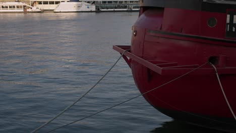 A-vibrant-red-boat-moored-on-a-sunny-day-in-Paris,-close-up-on-moorings