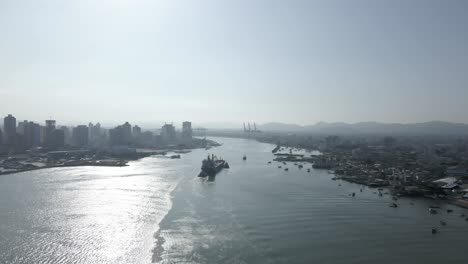 Big-Ship-Sailing-into-City-Harbor,-Sunny-Day,-Aerial-Dolly-In