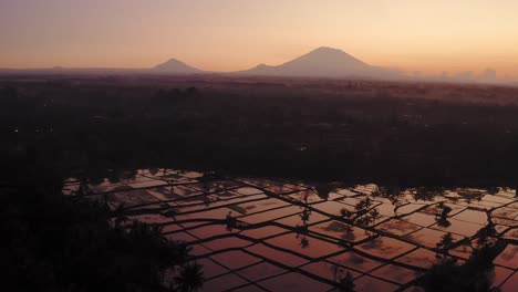 Luftwagen,-Der-Die-Reisterrassen-Von-Bali-Mit-Dem-Agung-Vulkan-Im-Hintergrund-In-Einem-Epischen-Orangefarbenen-Sonnenaufgang-Enthüllt