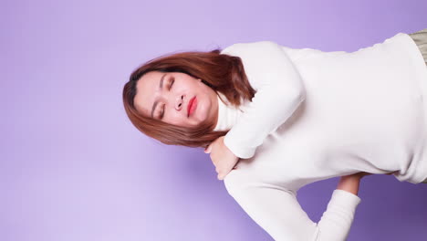 Vertical-of-Sick-tired-woman-suffering-intense-neck-and-shoulder-pain-touching-sore-stiff-muscles-and-frowning-from-ache-feeling-overworked-isolated-over-a-violet-background