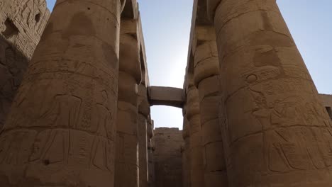 Tiro-Inclinado-Hacia-Abajo-A-Lo-Largo-De-Jeroglíficos-Detallados-Tallados-En-Columnas-Gigantes-De-Piedra-Arenisca,-Luxor