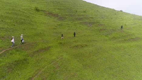 Gente-Caminando-En-La-Milla-Del-Sendero-De-Tierra-De-Montaña,-Paisaje-Natural-De-Pradera-Verde