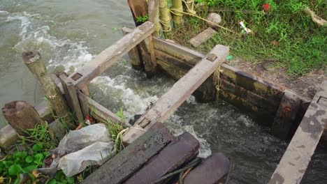 Sluice-water-inlet-outlet-gate-,-Water-seeps-into-the-fish-farming-area,-Panning-shot-to-the-flowing-water