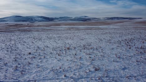 Flying-low-over-the-frozen-winter-field-during-sunset-in-winter-time