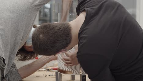 Detail-shot-of-two-scientists-checking-the-gradients-assembly-of-a-small-magnetic-resonance-imaging-device-wearing-COVID-19-face-masks