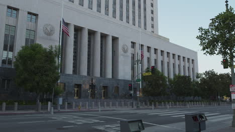 Revealing-shot-of-the-Los-Angeles-City-Hall-with-the-two-flags-of-the-USA-is-being-hoisted-in-front-of-the-entrance
