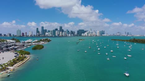 Aerial-view-over-boats-anchored-in-front-of-the-Brickell-skyline,-in-sunny-Virginia-Key,-Florida,-USA---tracking,-drone-shot