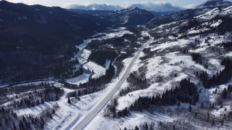 Winter-road-covered-in-snow-with-mountains-in-background