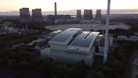 Aerial-view-orbiting-solar-rooftop-business-and-fossil-fuel-power-station-on-British-sunrise-skyline