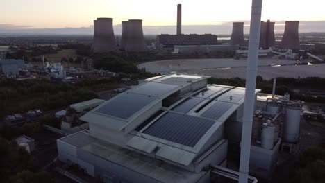 Vista-Inversa-Aérea-Edificio-Solar-En-La-Azotea-Y-Central-Eléctrica-De-Combustibles-Fósiles-En-El-Horizonte-Británico-Del-Amanecer