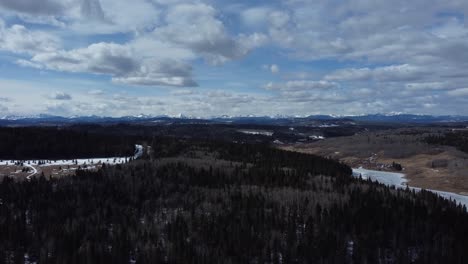 Drone-straight-up-shot-revealing-mountains-on-background-in-early-spring-forest-area