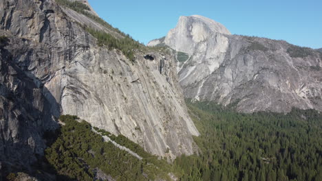 Yosemite-National-Park,-the-clip-shows-a-backward-movement-away-from-the-half-dome-and-a-mountain-cliff-with-a-cave