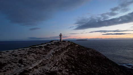 Drone-flyover-towards-Cape-Spencer-Lighthouse-handland,-sunset-on-seascape-horizon