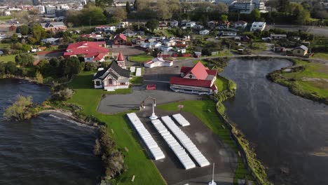 Beautiful-aerial-of-living-Maori-traditional-village-of-Ohinemutu-on-Lake-Rotorua-shore,-New-Zealand