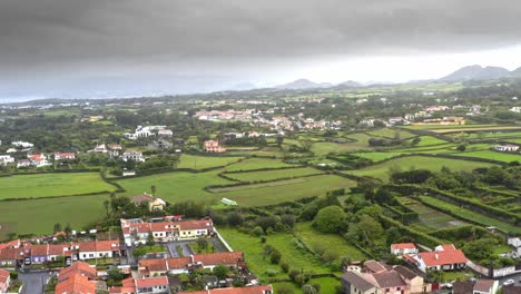Towns-in-picturesque-Azores-countryside-below-storm-clouds,-aerial