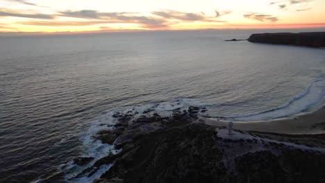 Orbiting-over-Lighthouse-on-scenic-sunset-landscape,-Cape-Spencer-Lighthouse-on-Cliff-over-Rocky-beachshore,-Australia