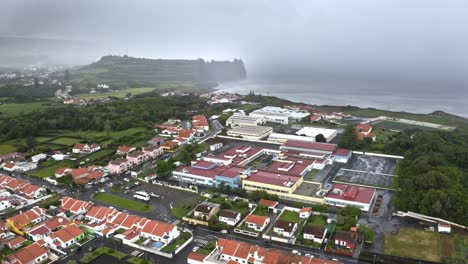 Storm-forming-above-sea-coast-and-town-in-Azores,-wide-aerial-shot