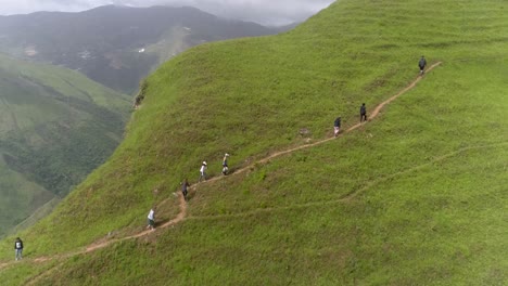 Grupo-De-Personas-Suben-A-La-Montaña-Verde-Caminando-En-Fila-Por-Un-Camino-De-Tierra,-Jarillo-Venezuela