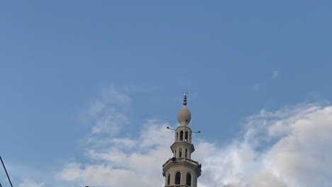 POV-Looking-Up-Mosque-With-Minaret-Against-Blue-Sky-With-Wispy-Clouds