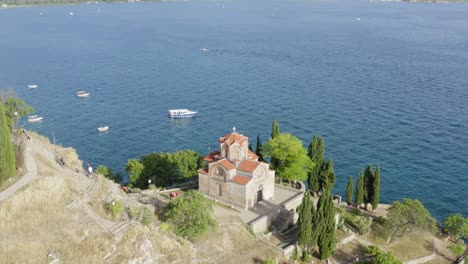 Drone-Volando-Lejos,-Iglesia-De-San-Juan-En-Kaneo-En-El-Lago-Ohrid-Macedonia-Del-Norte