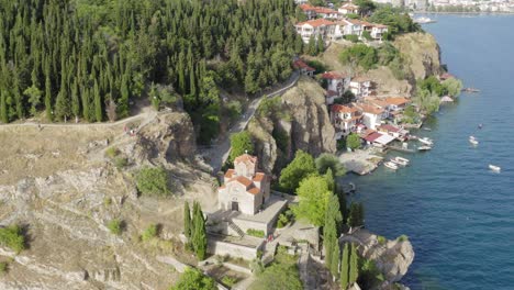 Drone-circling-around-St-John-Church-on-Lake-Ohrid-Cliff,-high-showing-walking-trails,-North-Macedonia