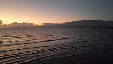 Surfers-at-sunrise-in-Maui-Hawaii-with-Haleakala-volcano-in-background