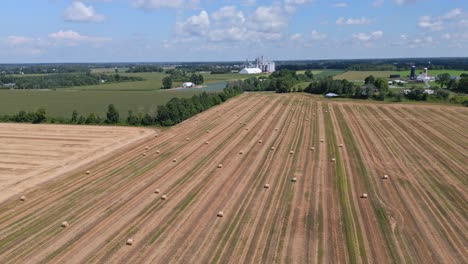 Backward-ascending-drone-shot-over-Ontario-farms-in-late-summer-with-hay-bails-and-silos