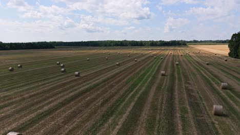 Drohnenvideo,-Das-Mit-Heuballen-über-Ein-Feld-Fliegt,-Während-Die-Sonne-An-Einem-Spätsommertag-In-Ontario,-Kanada,-Durch-Die-Wolken-Stößt