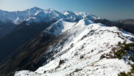 Man-standing-on-Mt-Fyffe-enjoying-stunning-alpine-scenery,-mountains-covered-in-snow